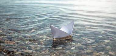 Büyük bir gölün berrak sularında taş gibi bir tabanı olan beyaz kağıt bir tekne..