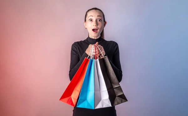 Женщина Удивленным Лицом Черном Платье Держит Разноцветные Бумажные Пакеты Покупками — стоковое фото