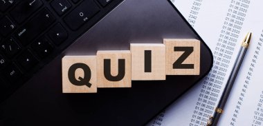 QUIZ kelimesi kalemin yanındaki klavyede tahta küplere kırmızı ile yazılır..