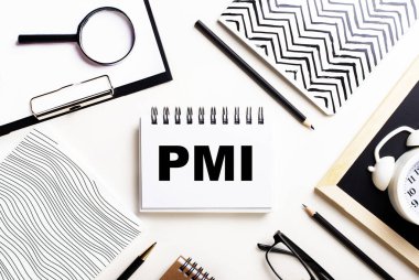 Bir ışık masasında defterler, bir büyüteç, bir çalar saat, bir gözlük ve bir kalem vardır. Ortasında da PMI yazılı bir defter var.