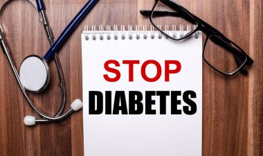 STOP DIABETES, steteskop ve siyah çerçeveli gözlüklerin yanındaki tahta bir arka planda beyaz kağıda yazılmıştır. Tıbbi konsept