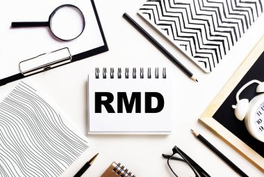Bir ışık masasında defterler, bir büyüteç, bir çalar saat, bir gözlük ve bir kalem vardır. Ortasında da RMD yazılı bir defter var.
