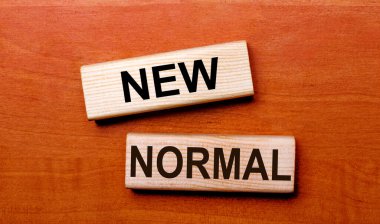 Tahta bir masanın üzerinde iki tahta blok var. YENİ NORMAL