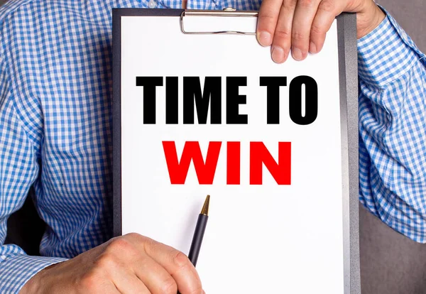 The man points with a pen to the phrase TIME TO WIN on a white sheet.