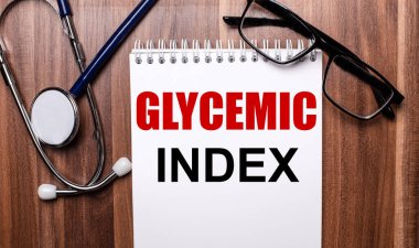 GLYCEMIC INDEX, steteskop ve siyah çerçeveli gözlüklerin yakınındaki ahşap bir arka planda beyaz kağıda yazılmıştır. Tıbbi konsept