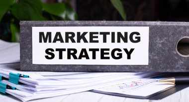 MARKETING STRATEGY, belgelerin yanındaki gri bir klasöre yazılmıştır. İş konsepti