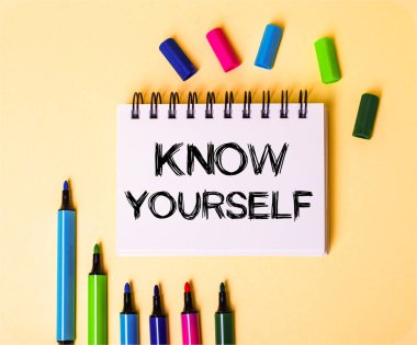 Kendinizi çok renkli kalemlerin yanında bej bir arkaplan üzerine beyaz bir not defterine yazdığınızı bilin