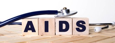 Ahşap arka planda AIDS sözcüğü ve steteskop olan tahta küpler. Tıbbi konsept