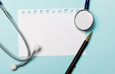 Stetoskop, beyaz kağıt ve açık mavi arka planda bir kalem. Metin ya da illüstrasyon eklenecek yer. Tıbbi konsept