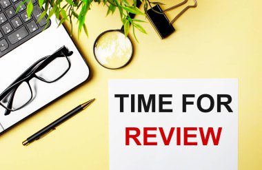 İnceleme Zamanı, dizüstü bilgisayar, kalem, büyüteç, gözlük ve yeşil bitkinin yanındaki açık sarı zemin üzerinde beyaz bir kağıt parçasına kırmızıyla yazılır..