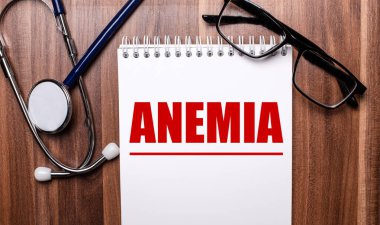 ANEMIA, steteskop ve siyah çerçeveli gözlüklerin yanındaki tahta bir arka planda beyaz kağıda yazılır. Tıbbi konsept
