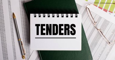 Masaüstünde raporlar, gözlükler, bir kalem, yeşil bir günlük ve üzerinde 