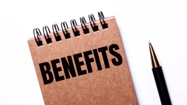 Hafif bir arkaplanda siyah bir kalem ve siyah yaylı kahverengi bir defter var.