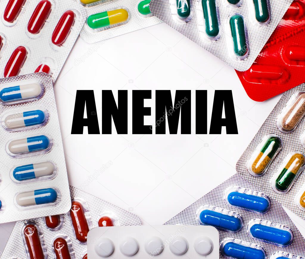 ANEMIA is written on a light background surrounded by multi-colored packages with pills. Medical concept