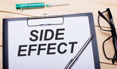 SIDE EFFECT siyah çerçeveli gözlük, kalem ve şırınganın yanında beyaz bir kağıt parçasına yazılır. Tıbbi konsept