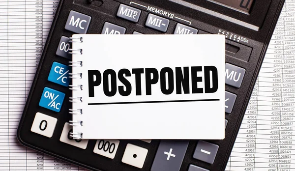 Masada raporlar, hesap makinesi ve üzerinde POSTPONED yazan bir kart var. İş konsepti