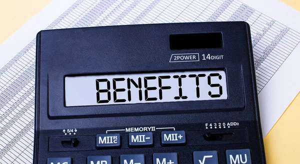 A calculator labeled BENEFITS is on the table near the report. Financial concept