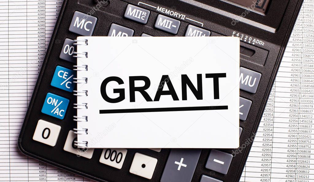 On the table are reports, a calculator and a card with the word GRANT on it. Business concept
