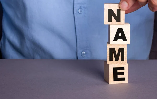 Man Blue Shirt Composes Word Name Wooden Cubes Vertically — Stock Photo, Image