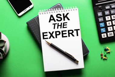 Yeşil bir arkaplanda - bir telefon, bir hesap makinesi ve üzerinde Uzman Ask yazılı bir günlük