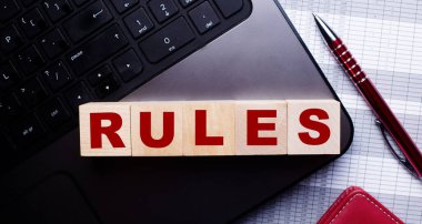 Klavyede, bordo renkli tükenmez kalemin yanında, üzerinde yazıt kuralları olan tahta küpler var.