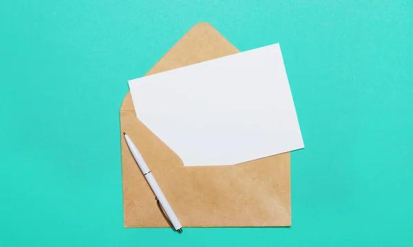 在绿色背景上 一个打开的工艺信封和一张用来插入文字或插图的空白卡片 — 图库照片
