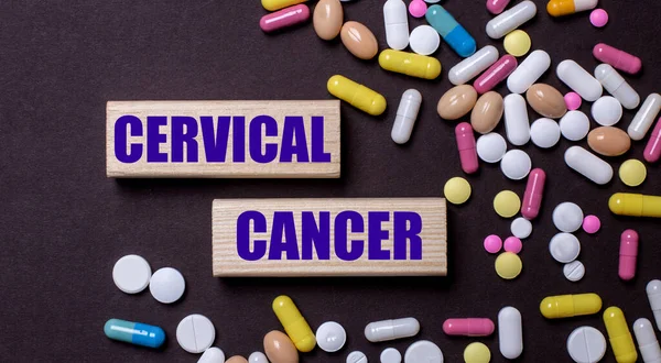 CERVICAL CANCER is written on wooden blocks near multi-colored pills. Medical concept