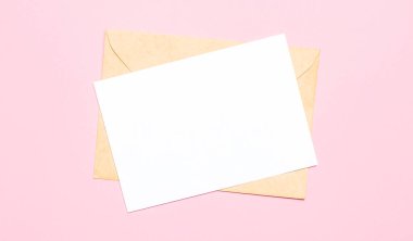 Açık pembe bir arkaplanda, bir zarf ve içinde mesaj ya da çizimler olan boş bir kart var. Yukarıdan görüntüle