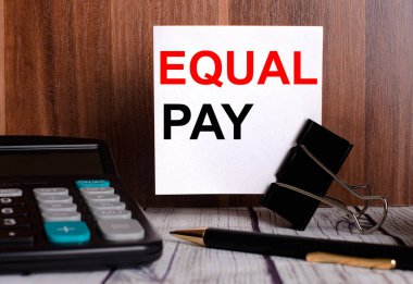 Eşit Ödeme, bir hesap makinesi ve kalemin yanındaki tahta bir arka planda beyaz bir karta yazılır..