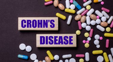 CROHNS hastalığı çok renkli hapların yanındaki tahta bloklara yazılmıştır. Tıbbi konsept