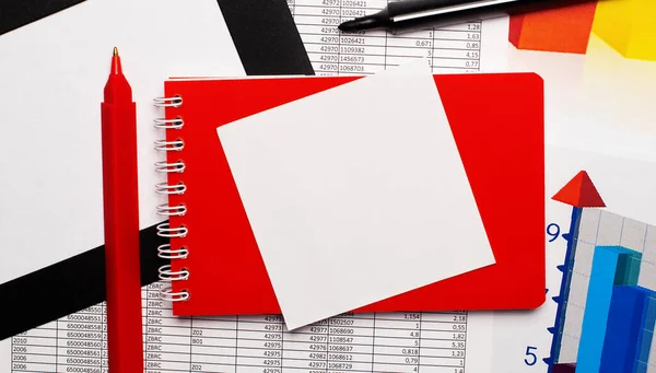 Red pen, black marker, color charts, red notepad and white blank paper with copy space on your desktop. View from above
