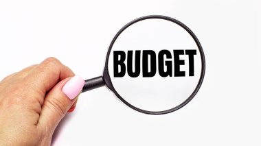 Kadın eli, üzerinde bütçe yazan bir büyüteç tutuyor.