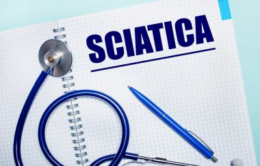 Açık mavi arka planda SCIATICA, mavi kalem ve steteskop yazılı açık bir defter var. Yukarıdan bak. Tıbbi konsept