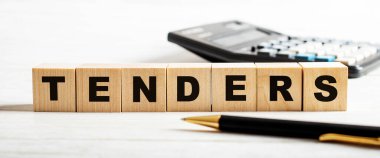 Hafif bir arka planda, bir kalem, hesap makinesi ve üzerinde TENDERS yazan tahta küpler. Odaklanmayın