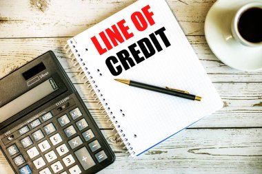 Kahvenin yanında beyaz kağıda ve açık ahşap bir masanın üzerinde hesap makinesi üzerine yazılmış bir CREDIT çizgisi. İş konsepti