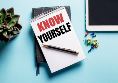 Açık mavi arka planda, bir saksı bitkisi, bir tablet ve kendini tanı yazılı bir haftalık var.