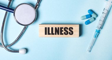 Mavi bir arka planda, steteskop, şırınga ve haplar ve üzerinde ILLNESS yazan ahşap bir blok. Tıbbi konsept