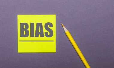 Gri bir arka planda, parlak sarı bir kalem ve üzerinde BIAS yazan sarı bir çıkartma.