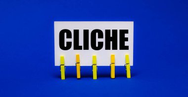 Sarı mandallar üzerine parlak mavi bir arkaplanda CLICHE yazılı beyaz bir kart var.