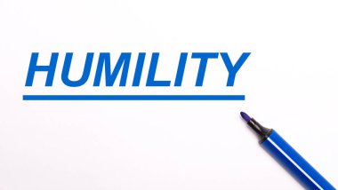 Açık bir arkaplanda, açık mavi bir keçeli kalem ve HUMILITY metni