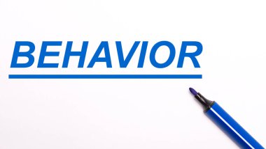 Açık bir arkaplanda, açık mavi bir keçeli kalem ve BeHAVIOR metni