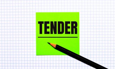 Üzerinde TENDER yazan yeşil bir çıkartma ve kareli kağıtta siyah bir kalem var..
