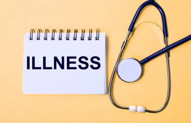 Bej bir arka plan, steteskop ve üzerinde ILLNESS yazan beyaz bir not defteri. Tıbbi konsept