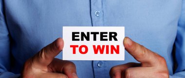 ENTER To WIN kelimeleri bir adamın elindeki beyaz kartvizitte yazılıdır. İş konsepti