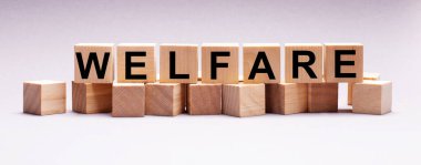 Hafif bir arkaplanda, WELFARE yazısıyla ahşap küpler