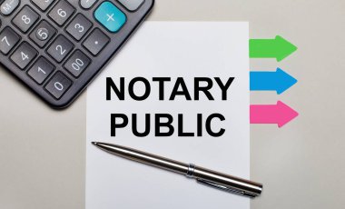 Açık gri bir arkaplanda, bir hesap makinesi, üzerinde NOTARY PUBLIC yazılı beyaz bir sayfa, bir kalem ve parlak renkli çıkartmalar. Yukarıdan görüntüle