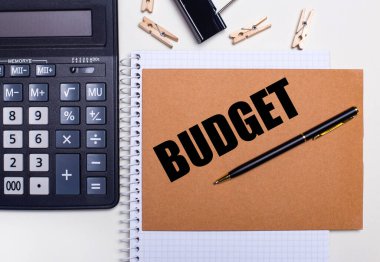 Masaüstünde bir hesap makinesi, bir kalem ve çamaşır mandalları var. Yanında da bir defter var. İş konsepti. Şablon. Yukarıdan görüntüle