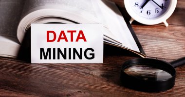 DATA MINING beyaz bir karta açık bir kitap, çalar saat ve büyüteç yanında yazıldı.
