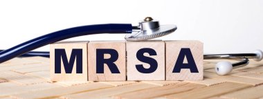 Ahşap arka planda MRSA sözcüğü ve steteskop olan tahta küpler. Tıbbi konsept