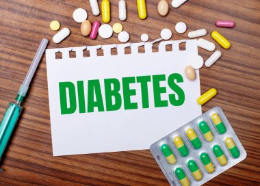 Tahta bir masada, bir şırınga, haplar ve üzerinde diyabet yazan bir kağıt. Tıbbi konsept